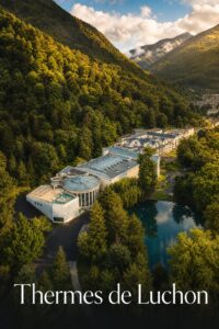 Vue aérienne du bâtiment historique des thermes de Luchon, encadré par les majestueuses montagnes des Pyrénées sous une lumière dorée d'après-midi, avec un bandeau semi-transparent foncé en bas affichant le texte 'Thermes de Luchon' avec ombre portée.
